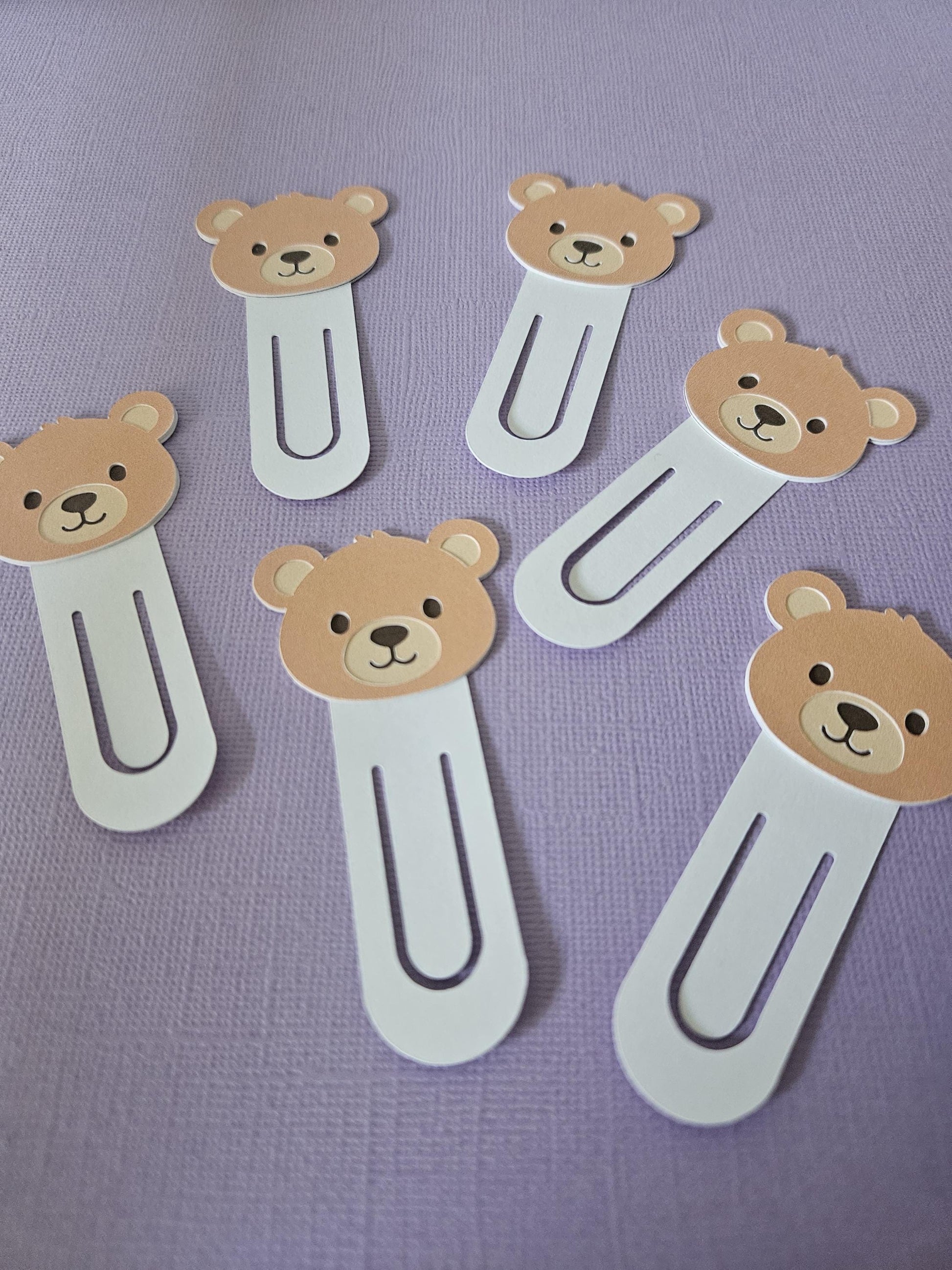 multiple brown bear bookmarks shown on purple page as background