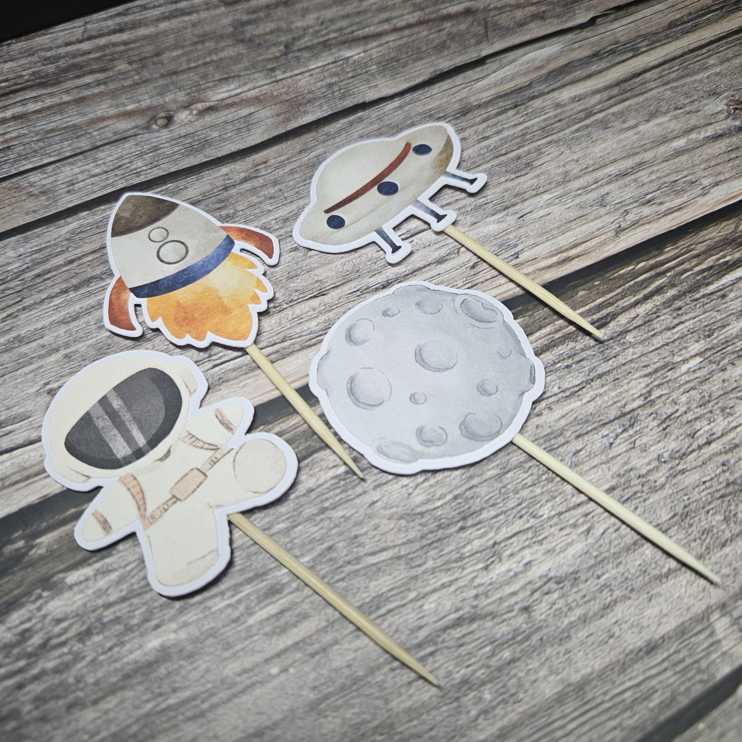Space cupcake toppers on vinyl background. astronaut, meator, ufo and rocket ship